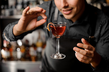 Smiling barman with a glass filled with alcoholic drink in the air