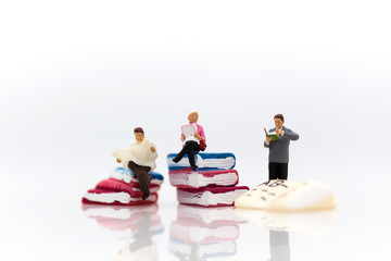 Miniature people: sitting on book and read book for increase knowhow using as learning never ends, education concept.