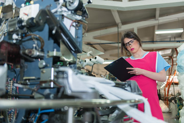 young woman controlling automated production of textile thread and cotton spinning