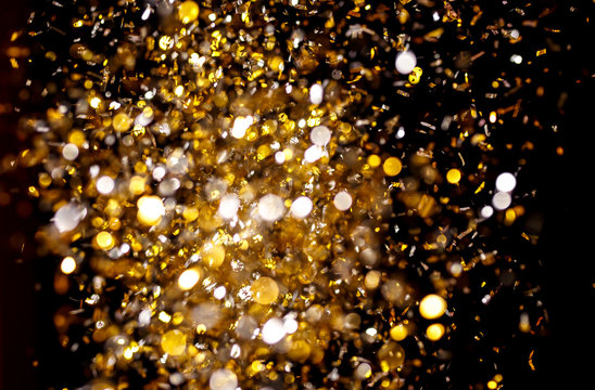 Photo of golden confetti on black background.
