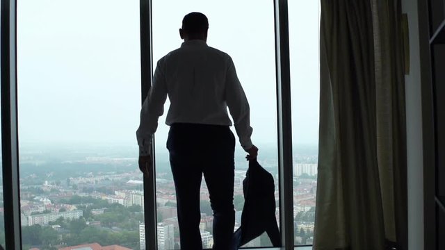 Young businessman admire view standing by window in office, super slow motion 240fps
