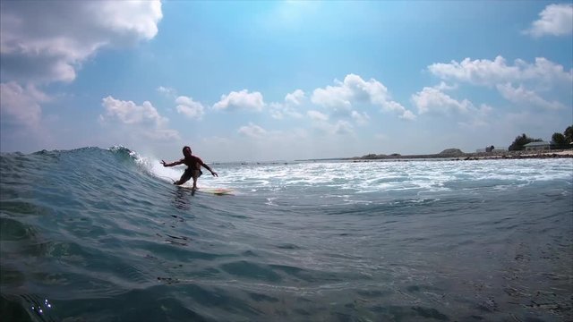 Surfer rides crystal clear ocean wave at sunny day and shows the Peace sign