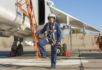 Military pilot in helmet stands near jet plane © Arrows