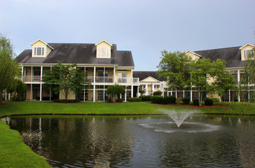 Southern modern architecture and vacation rentals background. Myrtle Beach suburb morning view with buildings around the pond with sprinkling fountain. South Carolina, USA.