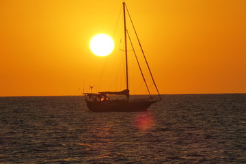 sail boat sunset on ocean red orange sinking sun in sea