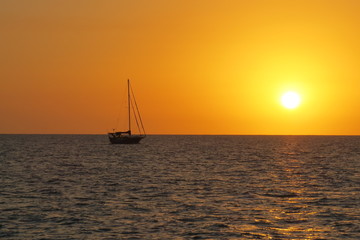 sail boat sunset on ocean red orange sinking sun in sea