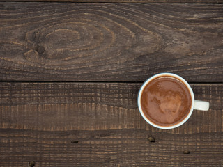 A cup of cocoa with foam on a wooden table
