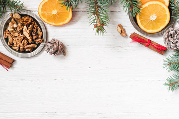 Fototapeta premium Orange in the cut, cinnamon, walnut on a white background. Branches of Christmas trees, gifts and bumps. A flat place, a place to copy, a top view. Holidays.