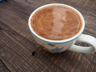 A cup of cocoa with foam on a wooden table