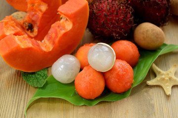 Longan and papaya ball-shaped pieces. Tropical fruits on a wooden background