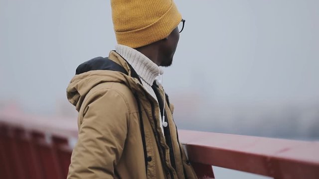 Young black man in a cap alone thinking on a bridge