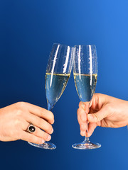 Male hands hold sparkling wine glasses.