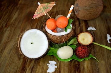 Tropical fruits: longan, rambutan and papaya ball-shaped pieces are lying in coconut. Cocktail ingredients