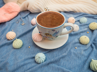 Cup of cocoa with foam and multi-colored bise on a wooden table