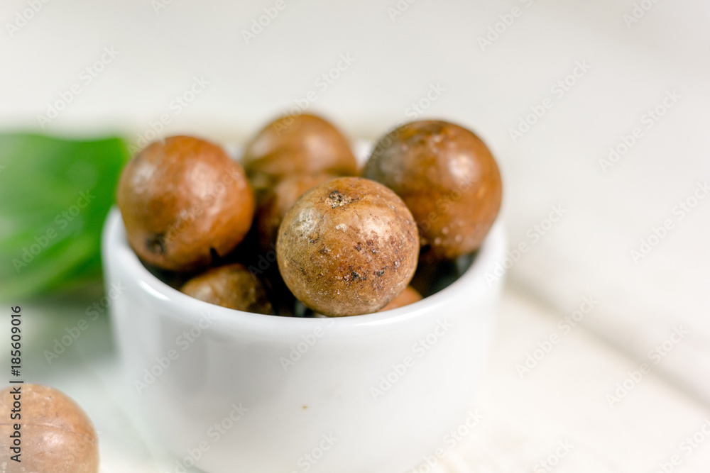 Canvas Prints white ceramic bowl with macadamia nuts over the wooden table.