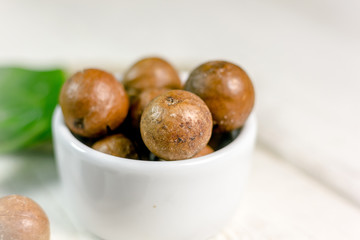 White ceramic bowl with macadamia nuts over the wooden table.