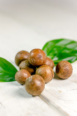 Fresh and ripe macadamia nuts over the wooden table.