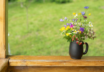 bouquet of wildflowers and strawberry berries stand on the terrace