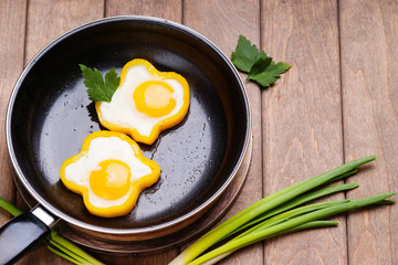 Bell pepper egg rings on a cooking pan, parsley and green onion  © bbstudio_ada