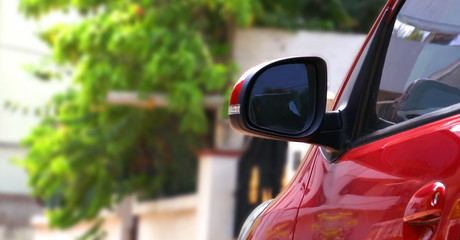 Abstract closeup of side rearview mirror on a red modern car.