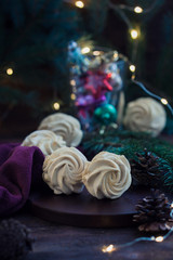 Homemade marshmallows or zephyr on the wooden background with festive lights