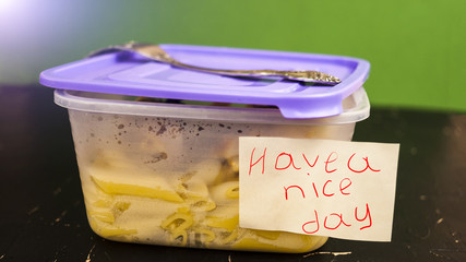 Open plastic container with lunch and fork and inscription on a piece of paper "Have a good day" concept of eating at work