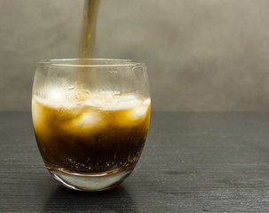 A cola drink poured into a glass with ice cubes.