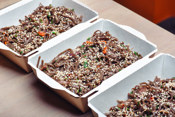 Buckwheat noodles with beef. In a white box on a wooden background. Close up shot