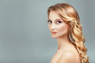 Beautiful woman face close up long curly blonde hair studio on beige