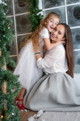 Mother and daughter in snowy winter studio hugging