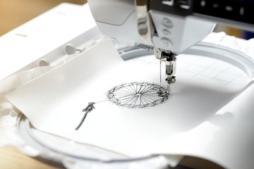 embroidery with embroidery machine - dandilon on white leatherette - view on embroidery process,...