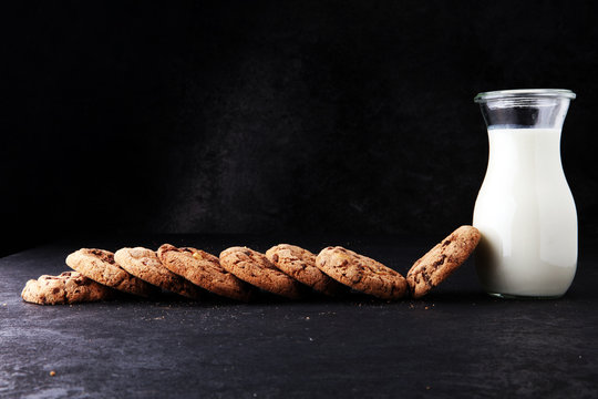 Chocolate chip cookies with milk on dark grey table