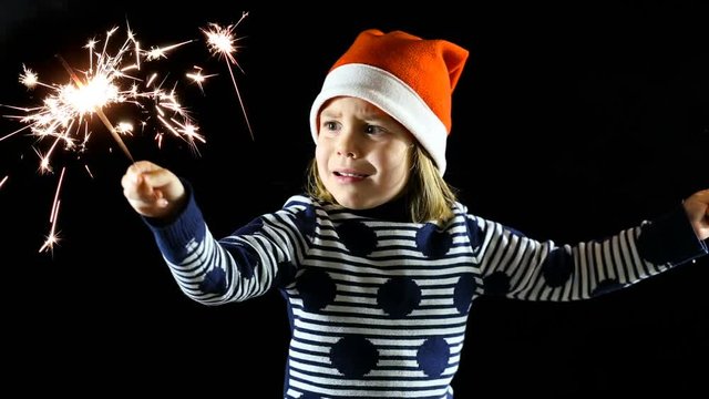 Cinemagraph Loop. Baby Hold Lights. A Child, A Girl Of 4-5 Years, Was Very Much Frightened Of Christmas Lights. Fear And Horror In Her Eyes. Christmas Sparklers. Dark Background.