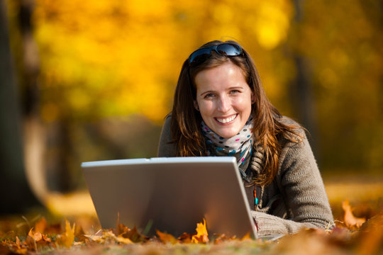 Attractive Young Woman In A Beautiful Fall Forest Working On Laptop