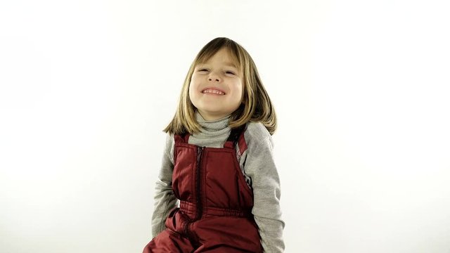 A small, very restless girl 4 - 5 years old, with blond hair, is photographed on her passport. The child is going on a trip with his parents. Studio, white background.