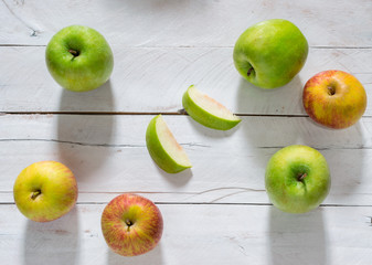 Green and red apples on top of a white wooden table background, whole and slices