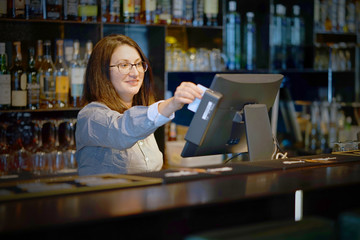 A restaurant worker registrating new order by cash-register. The concept of maintenance and service.