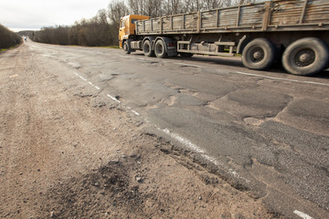 Bad Russian roads/truck with a trailer is driving along a broken road /Hole in the asphalt /risk of...
