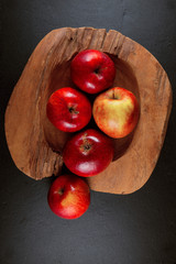 ripe red apples in a wood bowl on a slate plate background