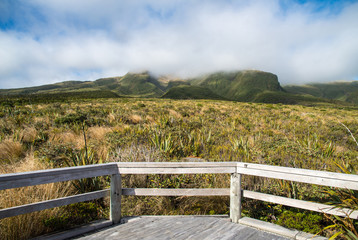 The viewing platform on the track to Ahukawakawa swamp in Mt.Taranaki during trekking in Pouakai crossing. Mt.Taranaki is behind the clouds.