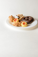 Zimtsterne, Lebkuchen, Engelsaugen, Makronen, auf weißem Teller vor weißem Hintergrund, Hochformat