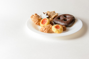 Zimtsterne, Lebkuchen, Engelsaugen, Makronen, auf weißem Teller vor weißem Hintergrund, Querformat