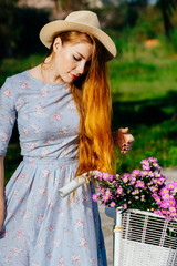 Beautiful red hair woman in a dress near a bicycle