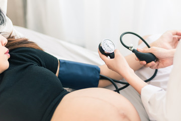 Female Obstetrician doctor  measuring blood pressure of the pregnant woman in the hospital....