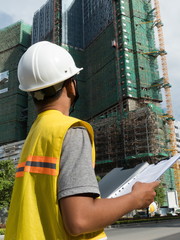 Medium vertical view Asian engineer looking up at nearby construction project