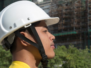 CU profile Asian construction manager with site in backgrond