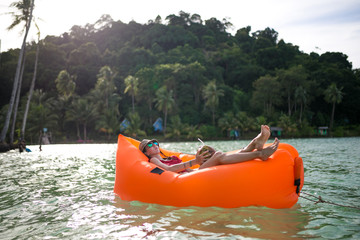 Young brunette woman, girl at the beach with Lazy Inflatable Air Bed, hammock, couch camping. ...
