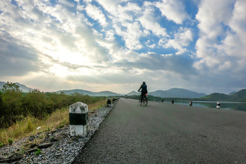 Woman ride bicycle on the road dam
