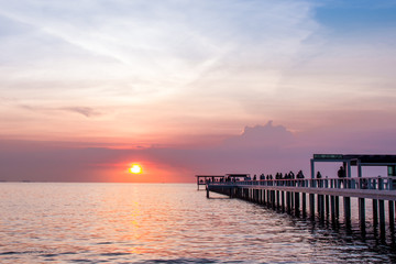 people on bridge into the sea while sunset