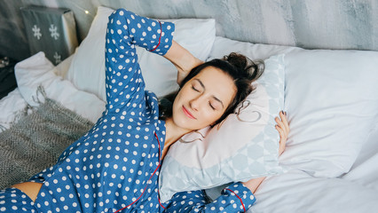 Cute happy woman relaxing home dressed in blue dots pyjamas